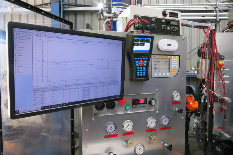 Hydraulic test bench with gauges, control panel, and computer displaying performance data during system diagnostics.